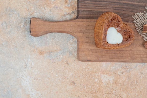 Heart shaped cake with cream on wooden board. 