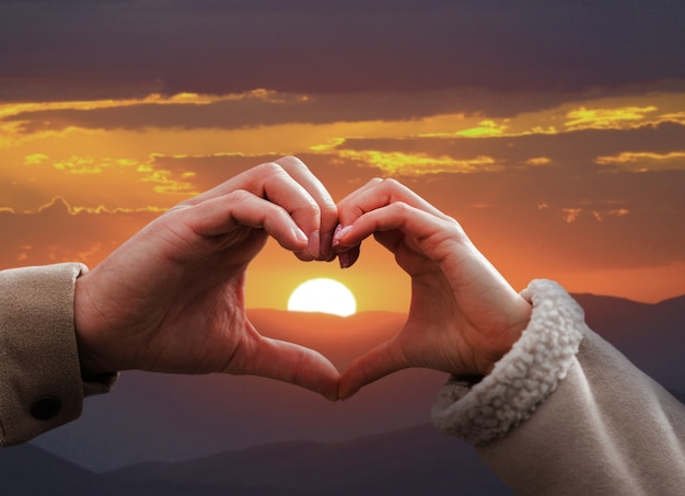 Heart-shaped hands on a sunset