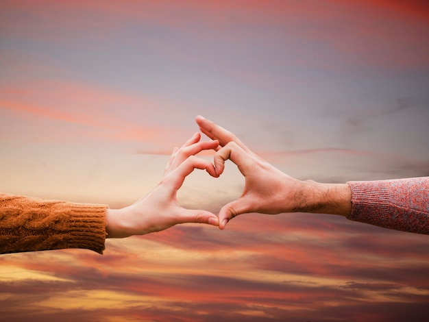 Heart-shaped hands on a sunset