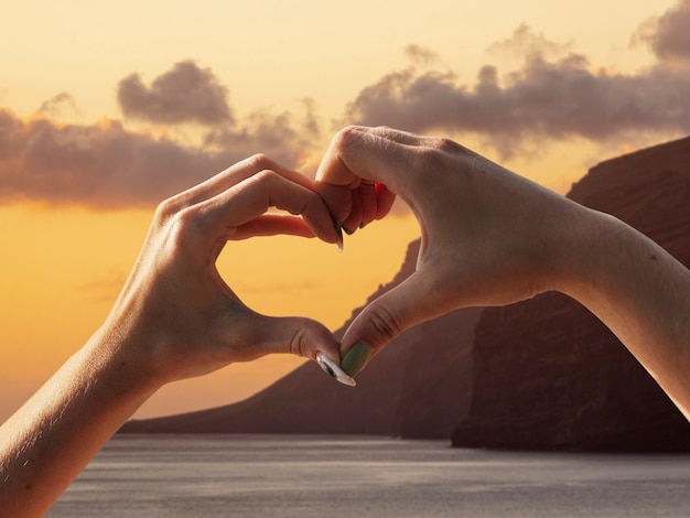 Free photo heart-shaped hands on a sunset