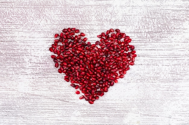 Heart shaped pomegranate top view on white d table