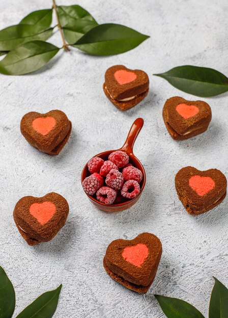 Heart shaped valentine cookies with frozen raspberries on light