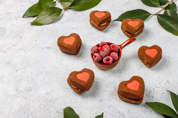 Heart shaped valentine cookies with frozen raspberries on light