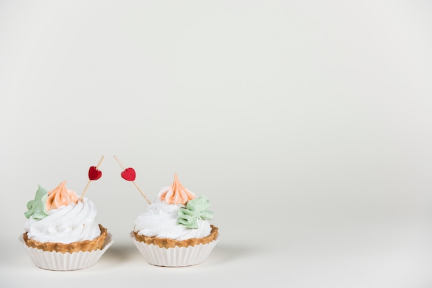 Free photo heart toppers in two cupcakes on table