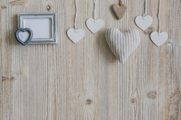 Free photo hearts hanging from ropes and a gray photo frame