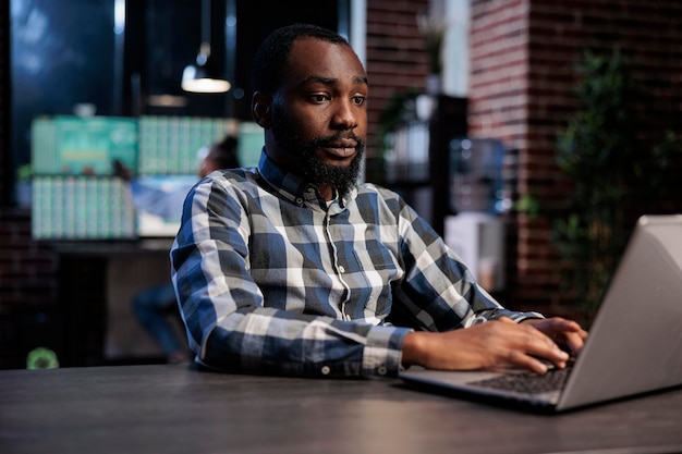 Hedge fund company trader using laptop to predict forex stock market trend and to analyze real time financial data. Trading agency employee in office workspace, working on opened position analysis.