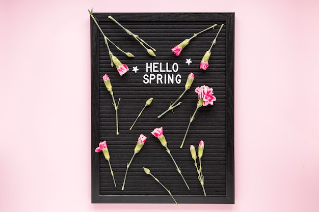 Free photo hello spring inscription with flowers on black board