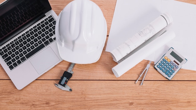 Helmet and blueprints near laptop