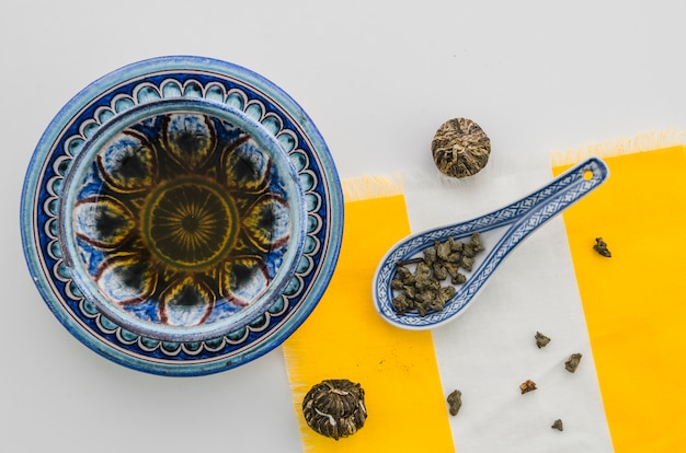 Free Photo herbal tea with floral blooming tea ball and oolong tea dust against white background