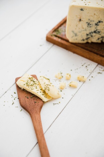 Herbs with cheese on spatula over the white wooden desk