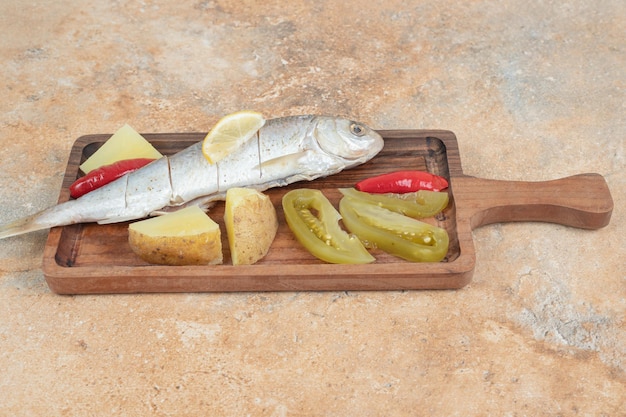 Herring with boiled potatoes and pickles on wooden board