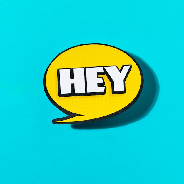 Free Photo hey text on yellow speech bubble on blue background