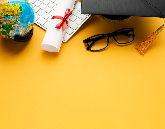 High angle of academic cap and glasses with globe