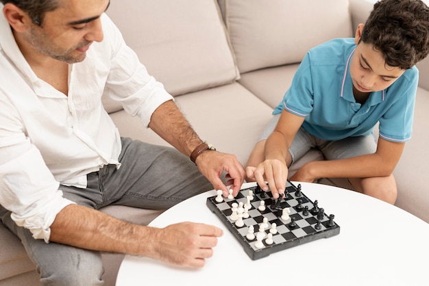 Free photo high angle adult and kid playing chess