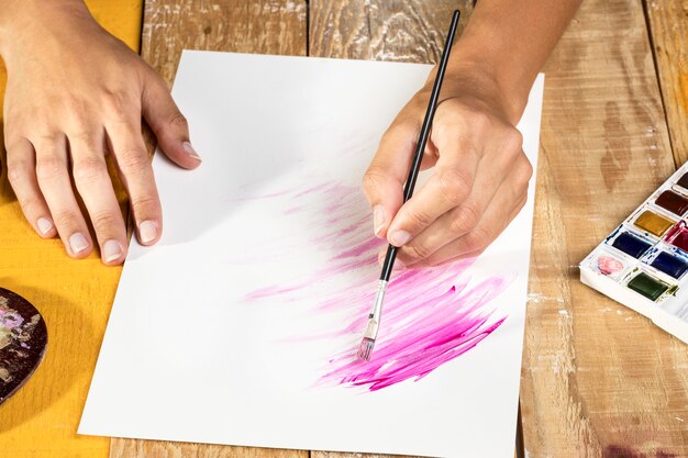 High angle of artist in studio painting on paper