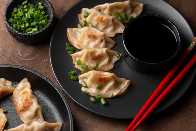 High angle of asian dumplings dish with chopsticks and herbs