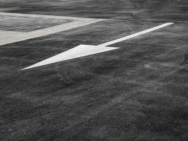 High angle of asphalt with white arrow