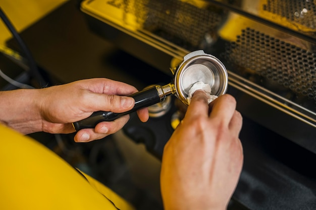 Free photo high angle of barista cleaning cup for coffee machine