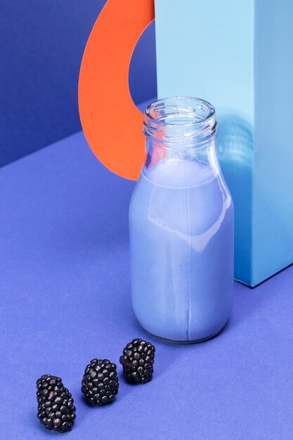 High angle blue soothie in glass bottle and blackberries