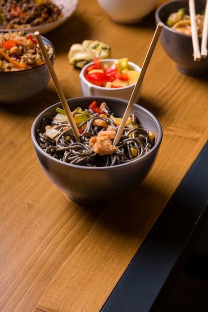 High angle of bowl of noodles with other asian food