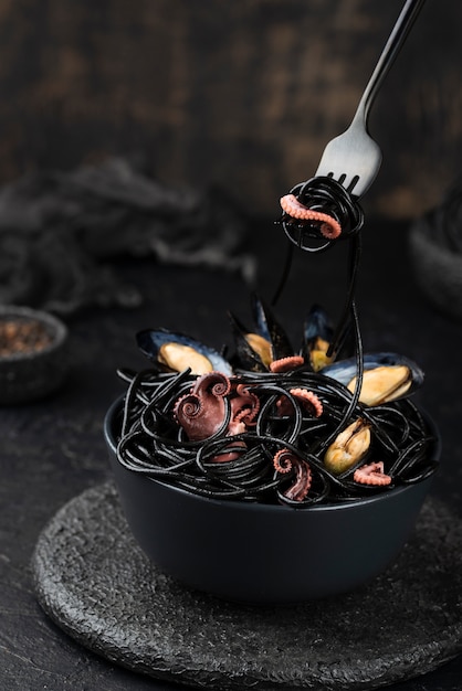 High angle of bowl with black spaghetti and squid