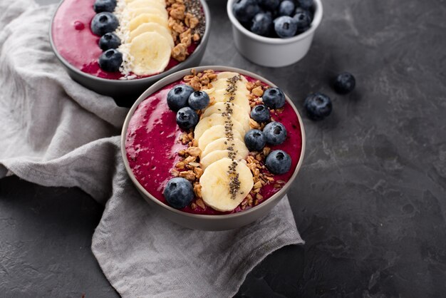 High angle of bowls with breakfast desserts and assortment of fruits and cereal