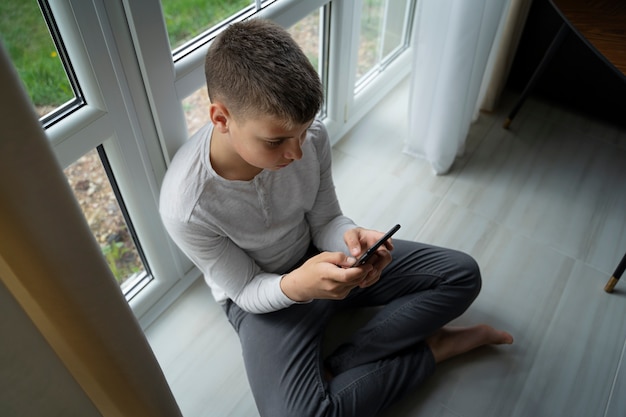 Free photo high angle boy holding smartphone