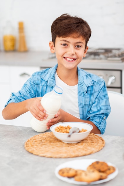 Free photo high angle boy pouring milk on cereals