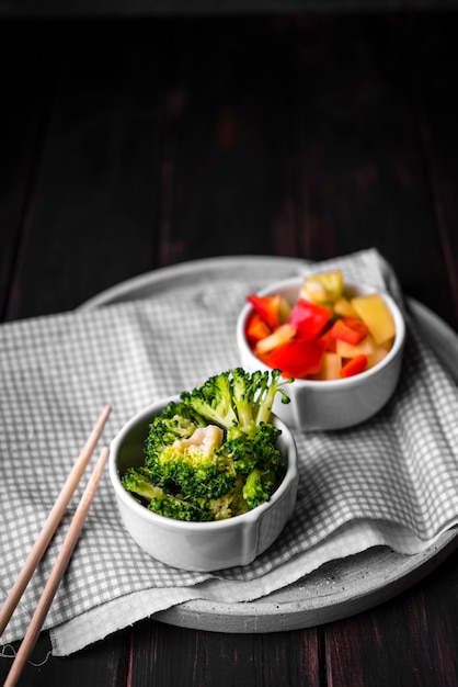 High angle of broccoli and bell pepper in cups on plate