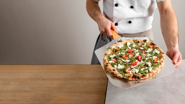 High angle chef holding peel tool with pizza