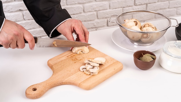 High angle of chef preparing and cutting mushrooms