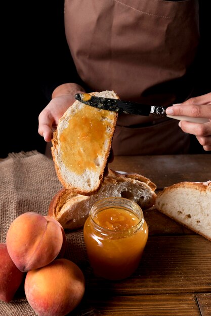 High angle of chef spreading peach marmalade on bread