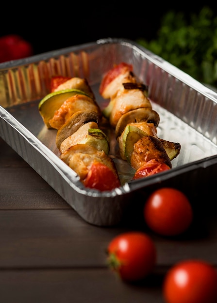 High angle chicken skewers on tray with cherry tomatoes