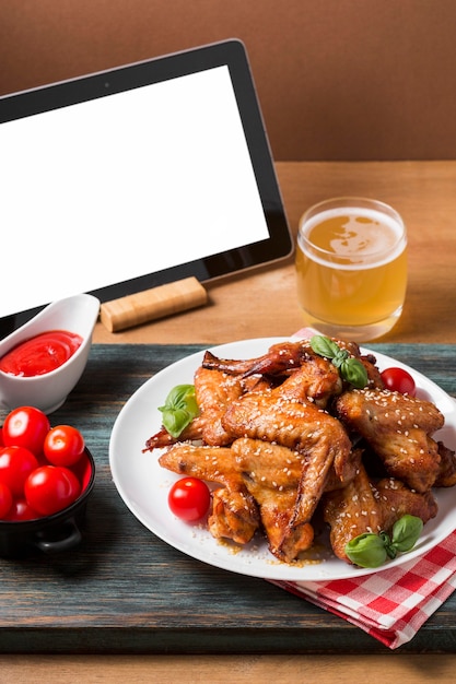 Free photo high angle chicken wings on plate with blank tablet