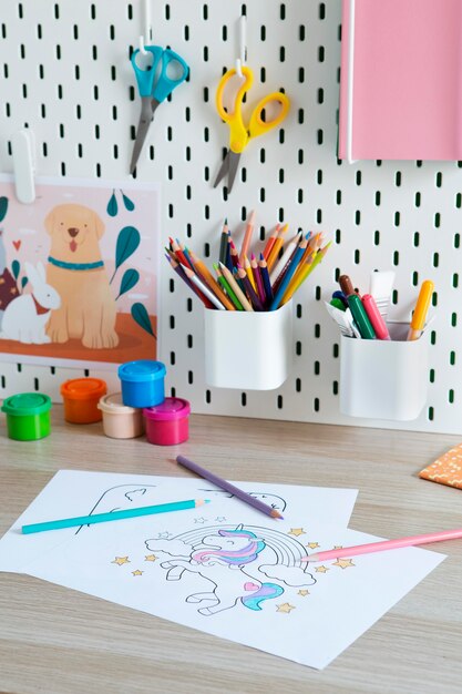 High angle of children's desk with drawings and pencils