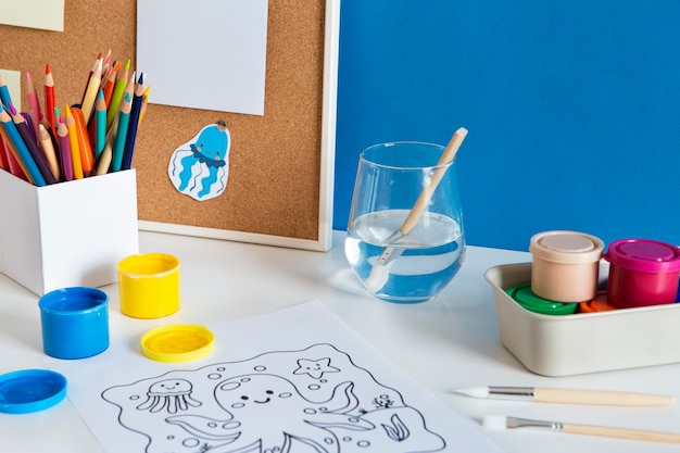 Free Photo high angle of children's desk with paint and drawing