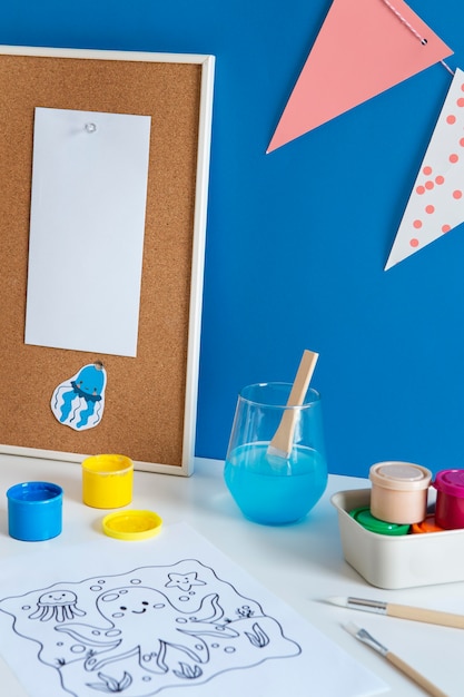 High angle of children's desk with paint and drawing