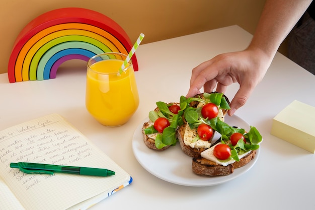 Free photo high angle of children's desk with sandwiches and orange juice