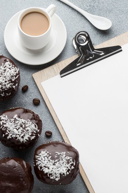 High angle of chocolate desserts with coffee and notepad