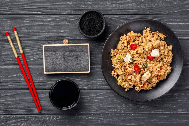 High angle chopsticks and rice with vegetables on plate with blank blackboard