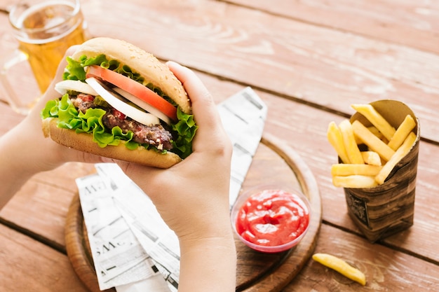 High angle close-up hands holding burger with burger with fries