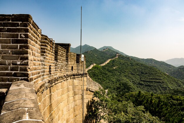 High angle closeup shot of the famous Great Wall of China surrounded by green trees in summer