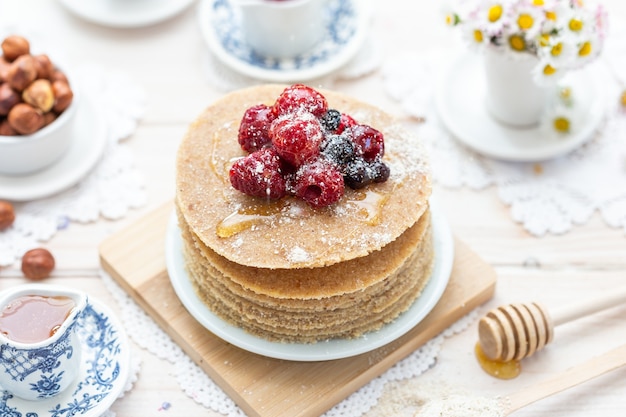 High angle closeup shot of raw vegan pancakes with honey and berries