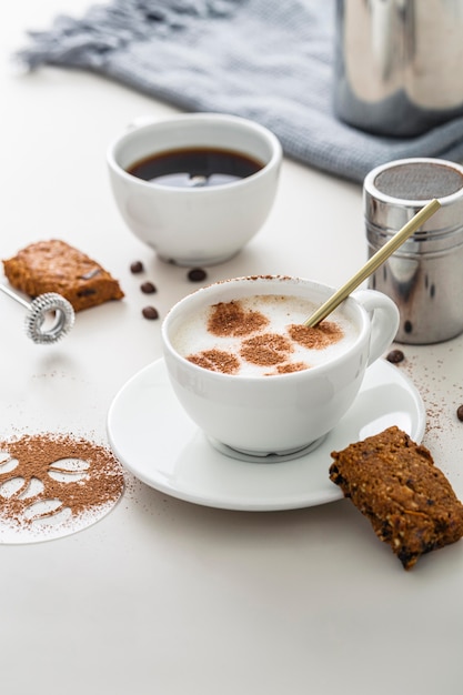 High angle of coffee cups with desserts and plate