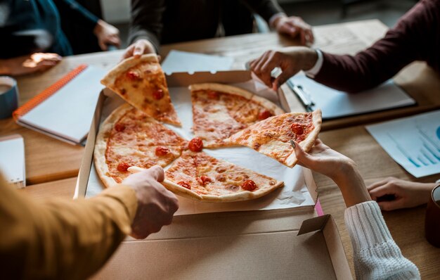 High angle of colleagues having pizza during an office meeting break