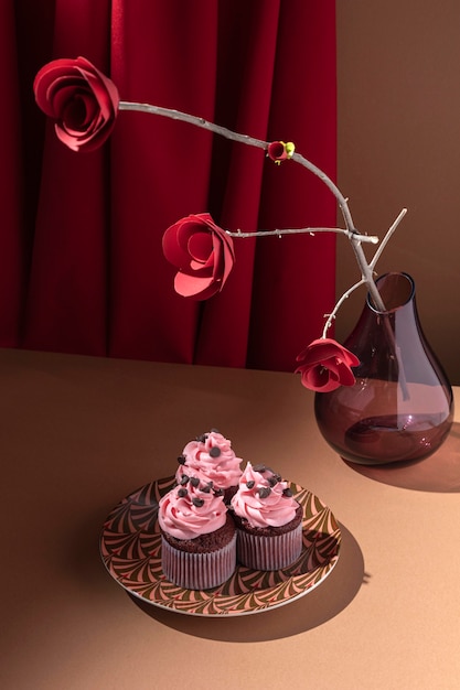 Free Photo high angle cupcakes on plate and paper roses