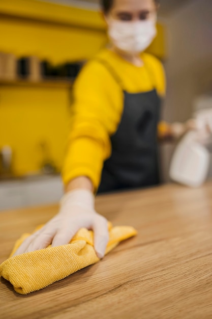 High angle of defocused barista cleaning surface while wearing medical mask