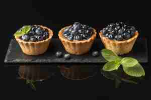 Free photo high angle of delicious blueberry tarts on slate with mint