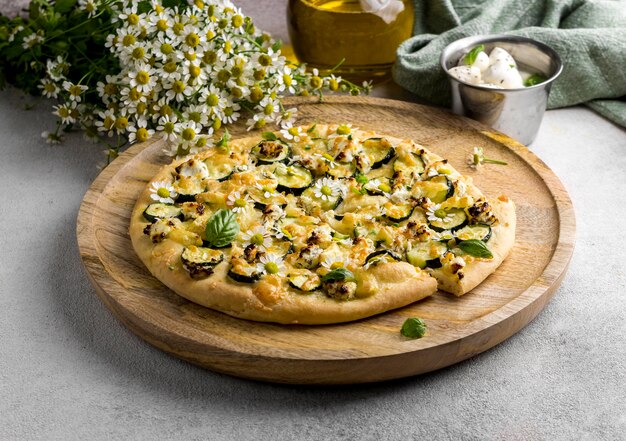 High angle of delicious cooked pizza with chamomile flowers