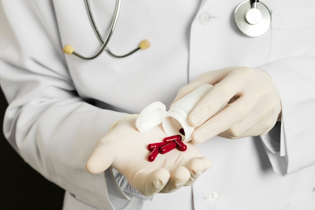 Free Photo high angle of doctor with surgical gloves holding pills